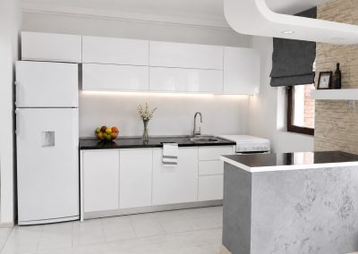 Bucătărie albă lucioasă cu blat de granit negru și bar cu finisaj decorativ tip beton
