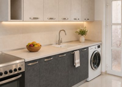 Bucatarie liniara cu corpuri sus bej si corpuri jos gri imitatie beton, blat crem si loc pentru masina de spalat