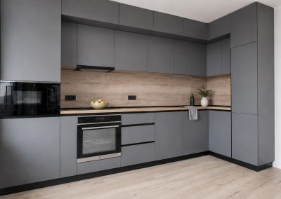 Bucătărie gri antracit mată, fără mânere, cu blat de lemn deschis și perete decorativ din stejar