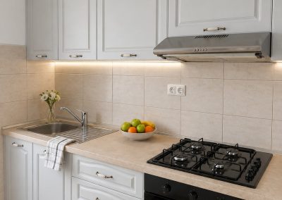 Bucatarie clasica gri deschis cu fronturi cu rama, blat crem, hota inox si plita pe gaz cu cuptor negru