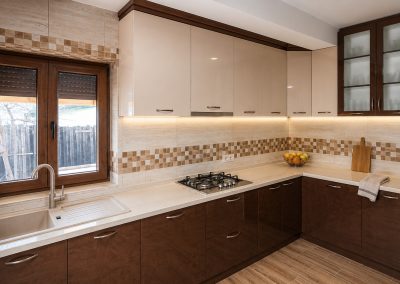 Bucătărie în L cu corpuri sus crem lucios, corpuri jos wenge, blat bej, vitrină cu sticlă mată și brâu de mozaic pe faianță