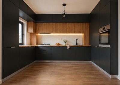 Bucătărie în U cu corpuri negru mat, rând de corpuri în decor stejar, blat de lemn și faianță hexagonală albă