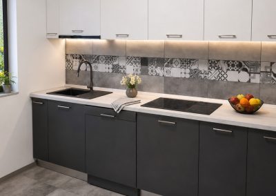 Bucătărie liniară cu corpuri sus albe și corpuri jos antracit mat, faianță decorativă patchwork și blat alb