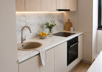 Bucătărie liniară cu corpuri sus în decor stejar, corpuri jos bej mat, blat și panou de spate imitație marmură și chiuvetă rotundă